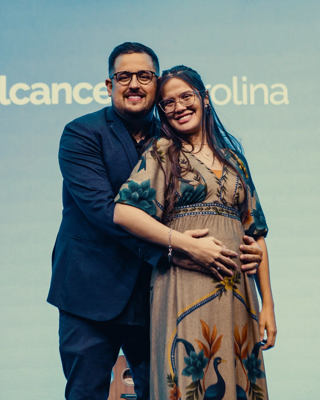 Nathália Carvalho e o esposo, Pr. Fellipe de Sá, sorrindo abraçados no palco da igreja